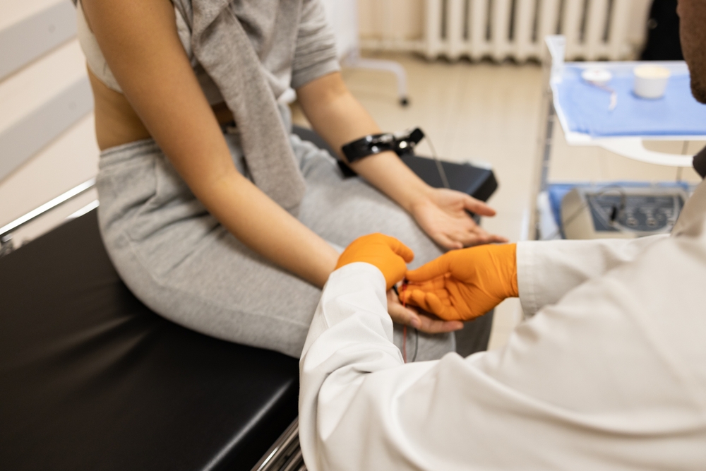 Technician performing an EMG test with electrodes placed on a patient’s arm to assess nerve and muscle function