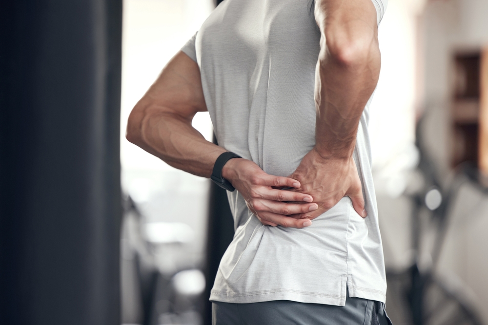 man grabs back and hip in pain