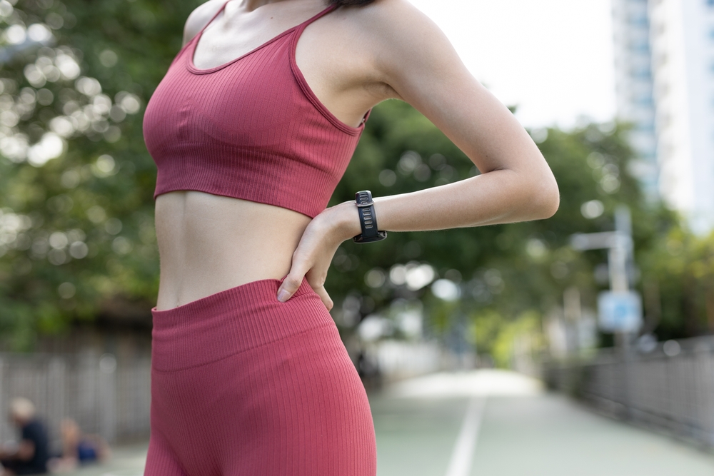 Woman in athletic wear stretching outdoors, representing women staying active and protecting their orthopedic health.